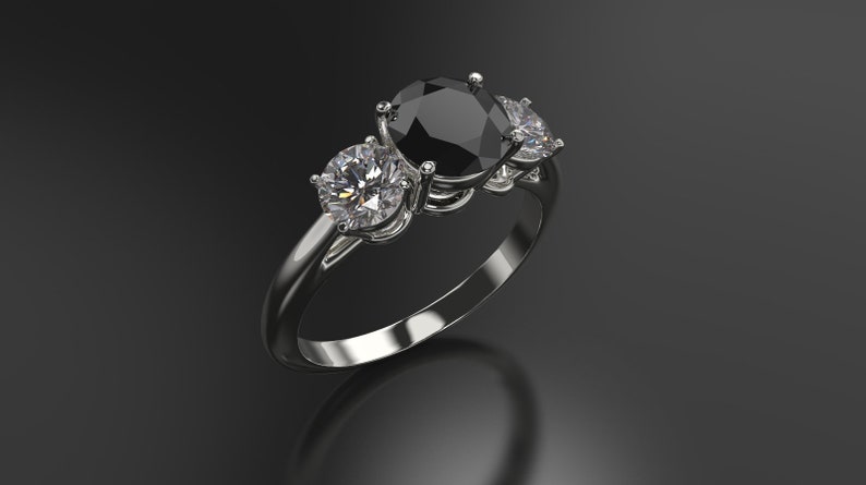 Pode incluir: Um anel de prata com uma grande pedra oval preta e duas pedras redondas brancas menores de cada lado.