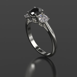 Pode incluir: Um anel de prata com um diamante preto no centro e dois diamantes brancos menores de cada lado.