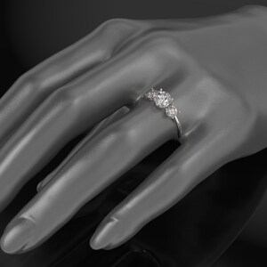 Pode incluir: Um anel de prata com cinco diamantes redondos engastados em fila. O anel est&aacute; em uma m&atilde;o de manequim.