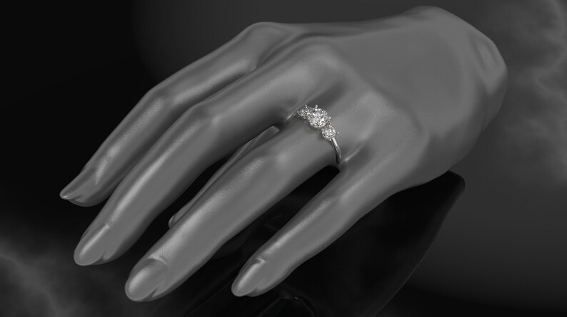 Pode incluir: Um anel de prata com cinco diamantes redondos engastados em fila. O anel est&aacute; em uma m&atilde;o de manequim.