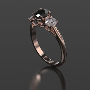 Pode incluir: Um anel de noivado de ouro rosa com uma pedra central de diamante preto e dois diamantes brancos menores de cada lado.