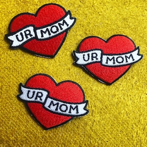 May include: Three red heart-shaped iron-on patches with white embroidered text that reads "UR MOM".