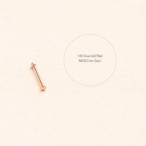 May include: A rose gold-filled micro stud earring. The earring is a small, straight bar with a rounded end on each side. The text in the image reads: "14K Rose Gold filled MICRO 1mm Stud!"