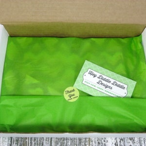 Puede incluir: Una caja llena de papel de seda verde con una peque&ntilde;a pegatina de agradecimiento y una tarjeta de visita que dice "Hey Diddle Diddle Designs etsy.com/shop/HRDBOUTIQUE".