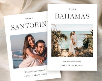 May include: Two white cards with black text and photographs. One card says "SANTORIN" and "Where we got engaged 20TH MARCH 2022". The other says "BAHAMAS" and "Our first anniversary 20TH MARCH 2023".