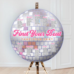 May include: A silver disco ball with pink and white text that reads "Find Your Beat Take Your Seat". The disco ball is divided into sections with names listed in each section. The sections are labeled "Wonderwall", "Mad Love", "You & Me", "Havana", "Perfect", "Summer", "Ms. Brightside", "Senorita", "Wanna", "Ocean".