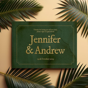 May include: A green guest book with a gold border and the text "Thanks for being part of our story, please sign our guestbook Jennifer & Andrew 29th October 2023".
