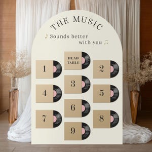 May include: A cream-colored wedding seating chart with the text "THE MUSIC Sounds better with you." Vinyl record-themed table assignments are numbered 1-9, with a "HEAD TABLE" designation.