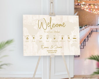 Puede incluir: Un cartel de bienvenida para una boda con un mapa del mundo de fondo. El cartel tiene una textura de madera rústica y está decorado con detalles dorados. El texto del cartel dice "Bienvenido a nuestra próxima aventura" e incluye los nombres "Emma & James" y la fecha "20 de agosto de 2021".