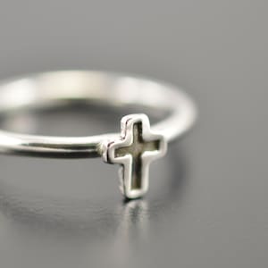 Peut inclure: Une bague en argent avec un petit motif de croix. La croix est en relief et a un centre creux.