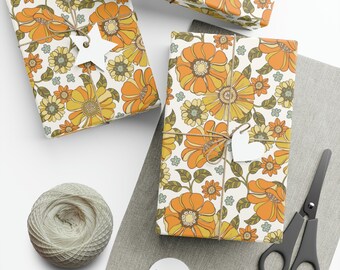 May include: Three gift boxes wrapped in white paper with a retro floral pattern in shades of orange, yellow, and green. The boxes are tied with twine and decorated with small white stars and hearts.