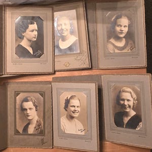 May include: Six vintage black and white photographs of women in formal attire. Each photo is framed in a brown paper frame with a gold border. The photos are arranged in two rows of three.