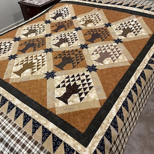 May include: A handmade quilt with a basket and star pattern. The quilt features squares with basket designs in shades of brown and tan, set against a brown background. Dark blue star accents and a plaid border complete the design.