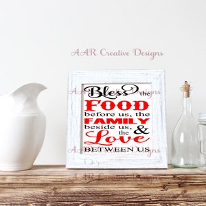 May include: White framed sign with black and red text that reads "Bless the FOOD before us, the FAMILY beside us, & the LOVE BETWEEN US".
