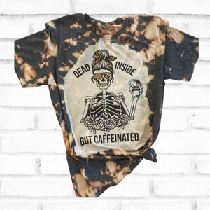 May include: Black and white tie-dye t-shirt with a skeleton graphic holding a coffee cup. The graphic says "Dead Inside But Caffeinated".