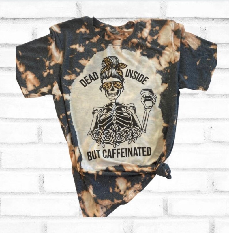 May include: Black and white tie-dye t-shirt with a skeleton graphic holding a coffee cup. The graphic says "Dead Inside But Caffeinated".
