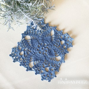 May include: A blue crocheted doily with a delicate floral design. The doily is made with a fine thread and has a lacy appearance.