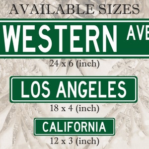 May include: Three green rectangular signs with white text. The top sign reads "WESTERN AVE" and measures 61 x 15 cm. Below it is a sign that says "LOS ANGELES" at 46 x 10 cm. The bottom sign reads "CALIFORNIA" at 30 x 8 cm.