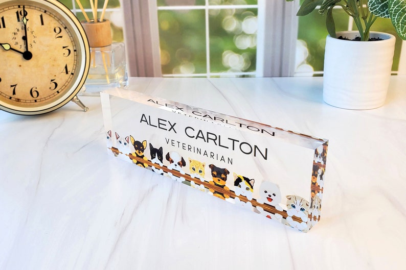 Peut inclure: Une plaque de nom de bureau en acrylique transparente avec le texte "Alex Carlton V&eacute;t&eacute;rinaire" et une bordure de chiens et de chats de dessin anim&eacute;.