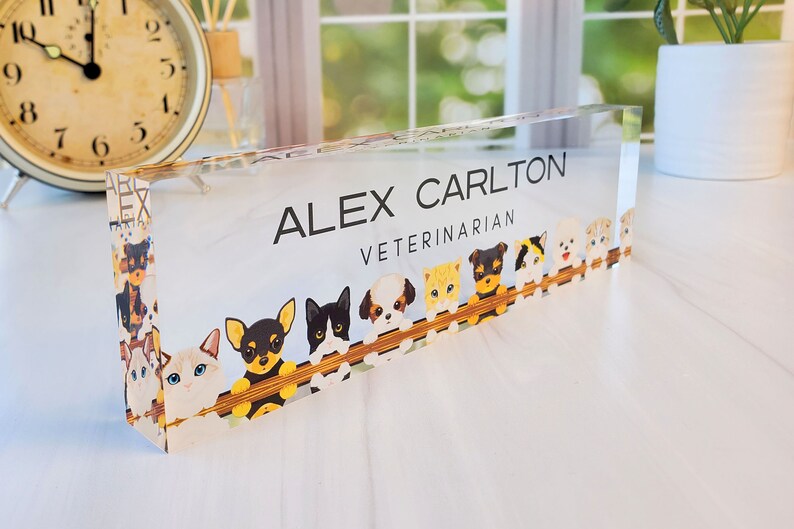 Peut inclure: Une plaque de nom de bureau en acrylique transparente avec le texte "ALEX CARLTON VETERINARIAN" et une bordure de chiens et de chats de dessin anim&eacute;.