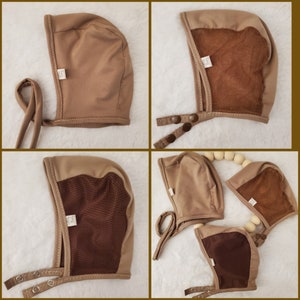 Peut inclure: Quatre bonnets de bébé bruns avec des liens. Deux bonnets ont une doublure en maille brune et deux ont une doublure en daim brune.