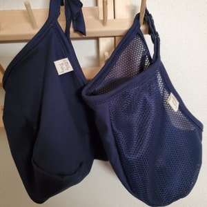 May include: Two dark navy blue fabric pouches with tie closures and snap buttons. One pouch is made of solid fabric, while the other features a mesh panel. Both items have a small white rectangular tag with the text Jelly Baby printed in black.