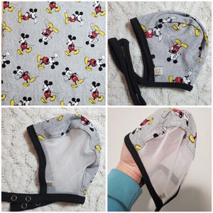 May include: A gray baby bonnet featuring a repeating pattern of Mickey Mouse in red, black, yellow, and white. The bonnet has a black trim and ties, with a white mesh lining. The bonnet is shown from multiple angles.