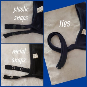 May include: A navy blue fabric accessory featuring three distinct closure options: black plastic snaps, silver-colored metal snaps, and fabric ties. Each section includes a small white tag with the text Gelly Baby visible on the edge of the fabric.