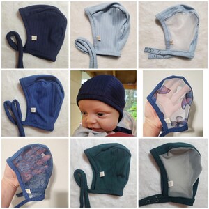 May include: A collage of baby bonnets in various shades of blue and green. The bonnets feature ribbed and solid fabrics, some with ties, and others with snap closures. One bonnet has a sheer overlay with butterfly designs.
