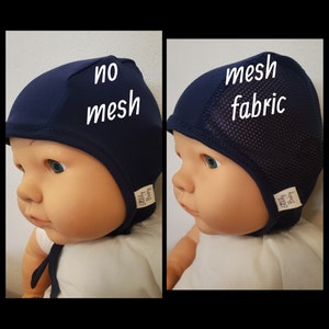 May include: Two navy blue baby bonnets shown on a doll. The left bonnet is solid fabric with the text no mesh. The right bonnet features a side panel of mesh fabric with the text mesh fabric. Both bonnets have a small white tag labeled Giddy Baby.