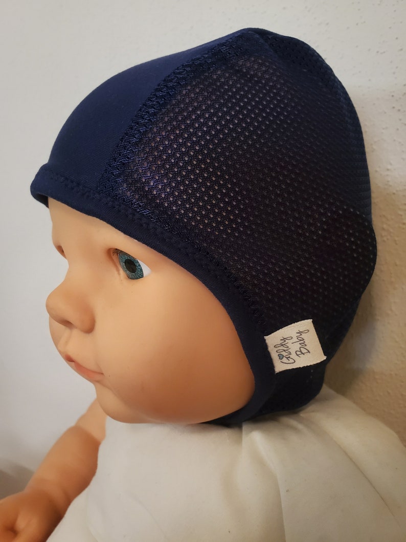 May include: A dark navy blue cap featuring a solid fabric front panel and a breathable mesh back panel. The cap includes a small white fabric tag on the side with the text Giddy Baby printed in black, and a solid navy blue trim along the bottom edge.