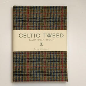 Può includere: Un taccuino rettangolare rivestito in tessuto tweed a quadri verdi, blu e rossi. Una fascia di carta color crema avvolge il centro, stampata con il testo CELTIC TWEED, BALBRIGGAN DUBLIN, un logo e The Irish Field Notebook.