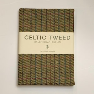 Può includere: Un taccuino rettangolare rivestito in tessuto tweed verde oliva con un motivo a quadri marrone, rosso e blu. Una fascia di carta color crema avvolge il centro, stampata con il testo CELTIC TWEED, BALBRIGGAN DUBLIN, un logo e The Irish Field Notebook.