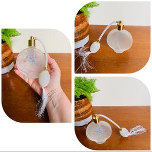 May include: A vintage glass perfume bottle with a white tassel and floral design. The bottle is frosted and has a gold top.