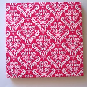May include: A pink and white damask patterned card stock paper. The pattern is a repeating design of white floral shapes on a bright pink background.