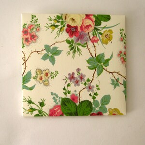 May include: A white envelope with a floral pattern featuring pink, yellow, and green flowers. The flowers are arranged in a repeating pattern on a white background.