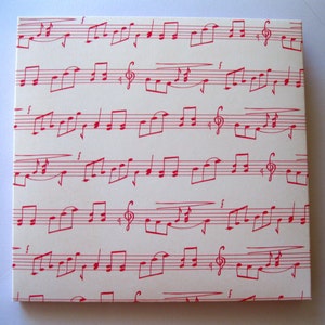 May include: White cardstock with a red musical note pattern. The notes are printed in a repeating pattern across the cardstock.