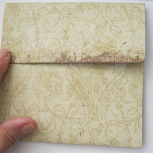 May include: A light beige envelope with a floral pattern. The envelope has a distressed look with brown accents.