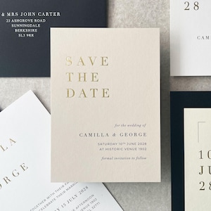 Könnte beinhalten: Cremefarbene Hochzeitseinladung mit goldfarbenem Schriftzug "Save the Date". Weitere Karten zeigen Namen, Adressen und das Datum 10. Juni 2028. Die Einladung ist für Camilla und George.