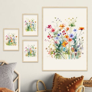 Op de afbeelding: Vier ingelijste aquarellen van kleurrijke wilde bloemen. Het grootste schilderij toont een boeket van roze, oranje, gele en blauwe wilde bloemen op een witte achtergrond. De andere drie schilderijen tonen kleinere boeketten van wilde bloemen in verschillende kleuren.