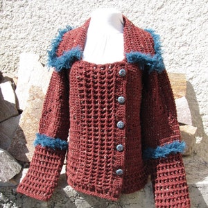 May include: A crocheted cardigan with a brown and blue color scheme. The cardigan has a textured waffle stitch and a fuzzy trim around the collar and cuffs. The cardigan has a button closure.