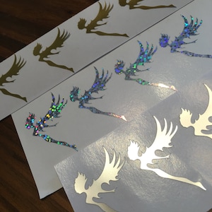 May include: Several sheets of stickers featuring a fairy design. The stickers are in gold, silver, and iridescent finishes. The fairies have outstretched wings and flowing hair, perfect for crafting or decorating projects.