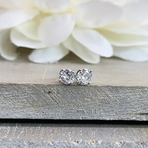 May include: A pair of silver stud earrings with clear round gemstones.