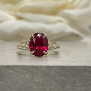 May include: A gold ring with a large oval ruby gemstone and smaller diamonds set in the band.