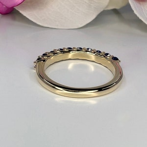 May include: A gold band ring with a row of blue sapphires set in the band.