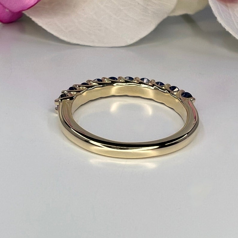 May include: A gold band ring with a row of blue sapphires set in the band.