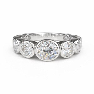 Puede incluir: Un anillo de plata con una serie de piedras preciosas redondas y claras, engastadas individualmente. El anillo tiene una superficie pulida y reflectante, y las piedras preciosas brillan intensamente. Dise&ntilde;o elegante y cl&aacute;sico.