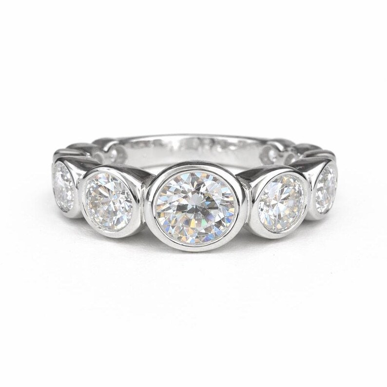 Puede incluir: Un anillo de plata con una serie de piedras preciosas redondas y claras, engastadas individualmente. El anillo tiene una superficie pulida y reflectante, y las piedras preciosas brillan intensamente. Dise&ntilde;o elegante y cl&aacute;sico.