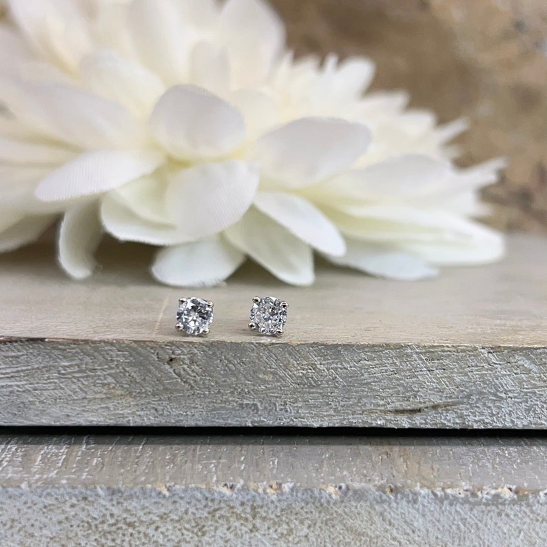 May include: A pair of silver stud earrings with clear round cubic zirconia stones.