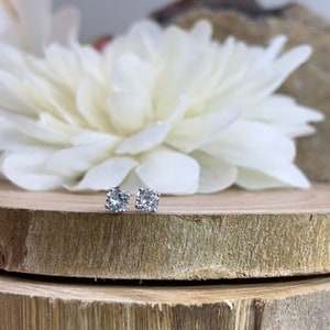 May include: A pair of silver stud earrings with clear round cubic zirconia stones.